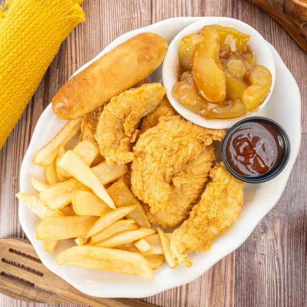 PoFolks fried chicken tenders, french fries, a corn dog, baked apples, and BBQ sauce on a white plate.
